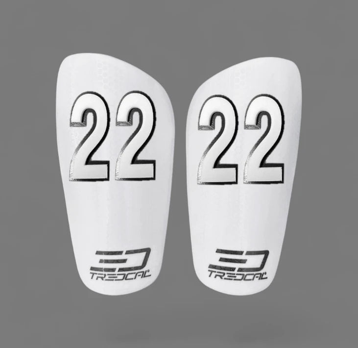 A pair of TREDCAL brand soccer shin guards with patented 3D number in arial font.
