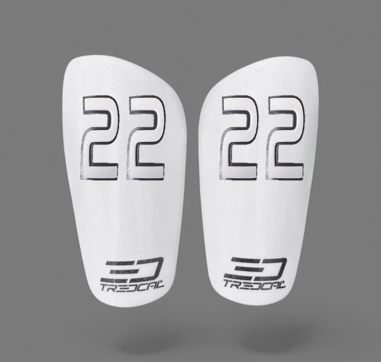 A pair of TREDCAL brand soccer shin guards with patented 3D number in pirulen font.