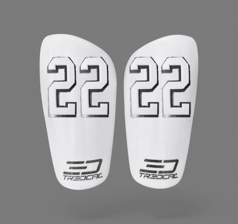 A pair of TREDCAL brand soccer shin guards with patented 3D number in varsity font.