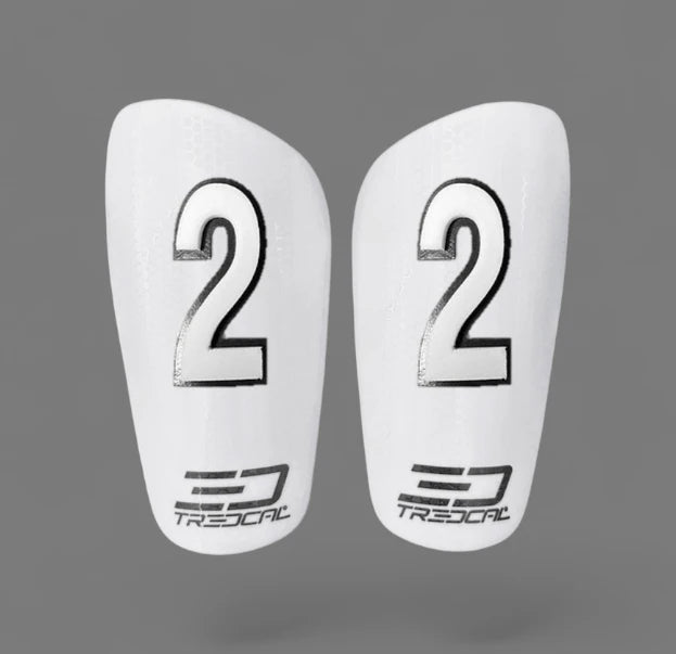 A pair of TREDCAL brand soccer shin guards with patented 3D single digit numbers on each guard in arial font.